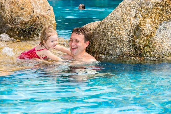 Ein aktiver Vater bringt seiner kleinen Tochter das Schwimmen im Pool eines Tropenbades bei. Sommerurlaub und Sportkonzept — Stockfoto