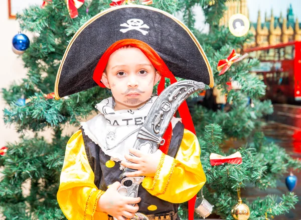 Malý chlapec, oblečený jako pirát pro Halloween na pozadí vánoční stromeček. Kluk v karnevalové kostýmy k Vánocům — Stock fotografie
