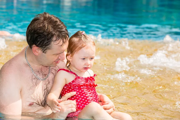 Ein aktiver Vater bringt seiner kleinen Tochter das Schwimmen im Pool eines Tropenbades bei. Sommerurlaub und Sportkonzept — Stockfoto