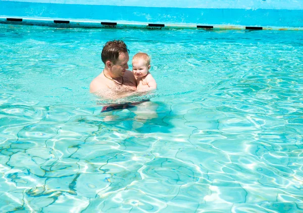 Active father teaching his child to swim in pool on tropical resort. Summer vacations and sport concept — Stock Photo, Image