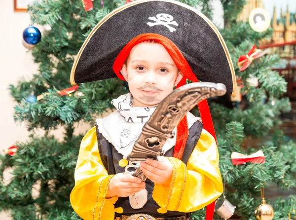 Niño pequeño vestido de pirata para Halloween en el fondo del árbol de Navidad. Niño con disfraces de carnaval para Navidad — Foto de Stock