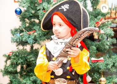 Küçük çocuk çocuk Noel ağacı arka plan üzerinde Cadılar Bayramı için korsan gibi giyinmiş. Karnaval kostümleri Noel için çocuk