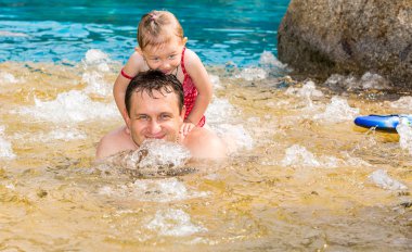 Tropikal tatil Havuzda yüzmek için yürümeye başlayan çocuk kızı öğretim etkin baba. Yaz tatillerini ve spor kavram
