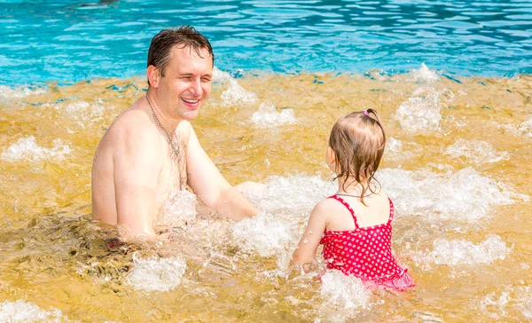 Active father teaching his toddler daughter to swim in pool on tropical resort. Summer vacations and sport  concept — Stock Photo, Image