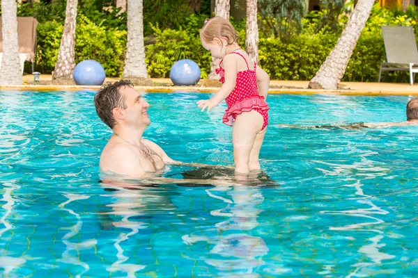 Pai ativo ensinando sua filha a nadar na piscina em um resort tropical. Férias de verão e conceito de esporte — Fotografia de Stock