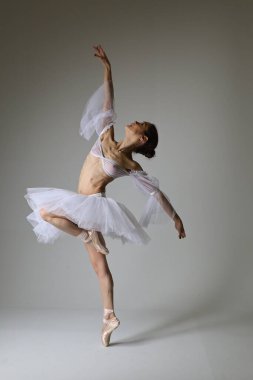 Stüdyoda poz veren bir balerinin fotoğrafı.