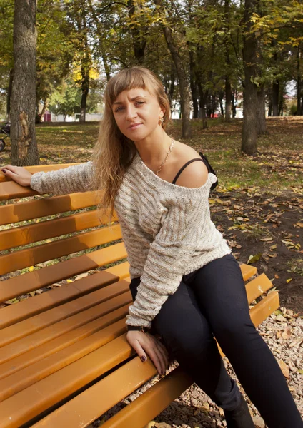 Young girl sitting on a yellow bench — Stock Photo, Image