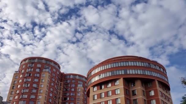 Современный жилой дом с полукруглыми крышами и белыми кучевыми облаками в голубом небе над головой — стоковое видео