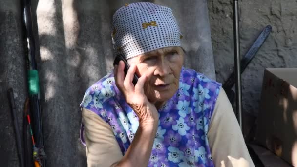 Славянская старшая сельская женщина по телефону в деревне — стоковое видео