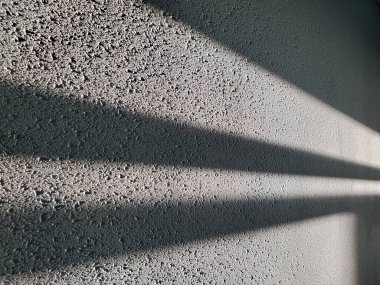 Geometrik desenli ve üçgen çizgili soyut bir arkaplan. Gri lekeli yüzeyi, ışık çizgileri ve gölgesi olan pürüzlü alçı duvar.