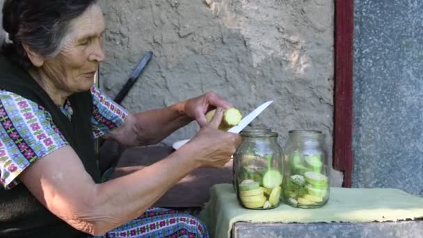 Elderly woman slice squash and put into jar — Stock Video