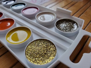 Sulu boya malzemelerinin yepyeni paletinin parlak altın parıltılı boyasına seçici bir odak.