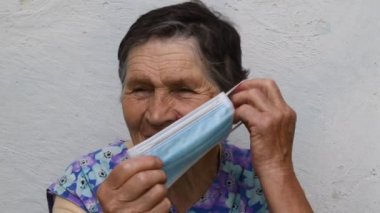 Yaşlı kadın nasıl uygun bir şekilde maske takılacağını gösteriyor.