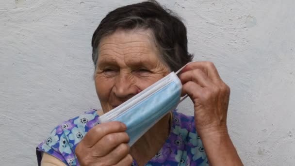 Oude dame laat zien hoe je een masker moet dragen op de juiste manier — Stockvideo