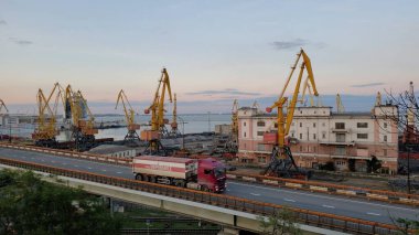 Liman kargo terminalleri ve sarı yükleyici vinçler. Kırmızı kamyonlu üst geçit yolu. Avrupa 'nın Karadeniz kıyısındaki sanayi bölgesi. Odessa, Ukrayna, 10 20 2020