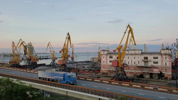 Port cargo terminals and yellow loader cranes. Overpass road and cargo vehicle traffic time lapse. Maritime port landscape in harbor of European Black sea coast. Odessa, Ukraine, 10 20 2020