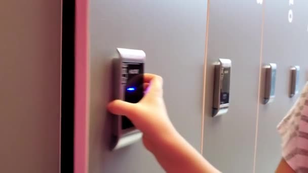Small girl opens locker by magnet bracelet — Stock Video