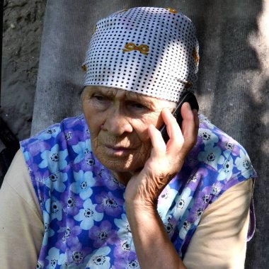 80 yaşında, elinde cep telefonu olan geleneksel giysili bir kadın portresi. Kırsal kesimde, elinde buruşuk bir telefon olan son sınıf öğrencisi bir kadın. Büyükannenin endişeli duygusal yüzü.