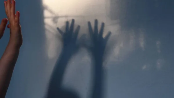 Blur shadows of child hands on wall. Game with light and shadow. Dark spooky silhouettes of hands for Halloween concept