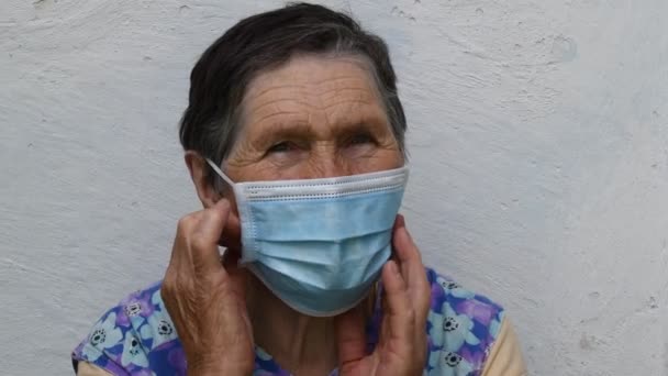 Senior woman takes off and folds disposable mask from wrinkled face — Stock Video