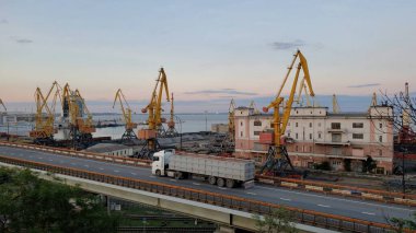 Liman kargo terminalleri ve sarı yükleyici vinçler. Yükseltilmiş yoldan geçen beyaz konteynır kamyonu. Avrupa 'nın Karadeniz kıyısındaki liman arazisi ticareti. Odessa, Ukrayna, 10 20 2020