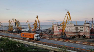 Yükseltilmiş yoldan geçen turuncu konteynır Hapag Lloyd 'u taşıyan kargo aracı. Avrupa Karadeniz Sahili 'nin liman manzarası. Odessa, Ukrayna, 10 20 2020
