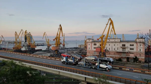 Liman manzarası ve karavan ön planda yükseltilmiş yoldan ilerliyor. Otomobil nakliye karavanıyla üst geçit. Avrupa Karadeniz kıyılarının deniz manzarası. Odessa, Ukrayna, 10 20 2020