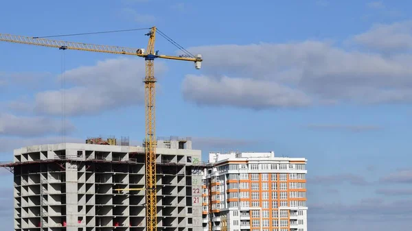 Construction site at rooftop of unfinished skyscraper with big tower crane lifting up construction materials. Urban real estate development. Heavy construction machinery