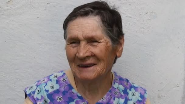 Portret van een glimlachende oudere vrouw die haar grijze haar aanraakt om haar korte kapsel glad te strijken — Stockvideo