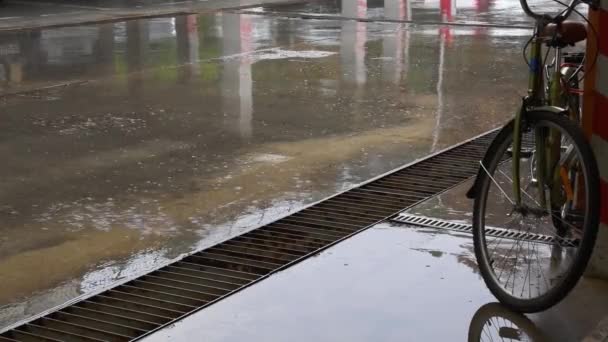 Versa pioggia da pozzanghere sul terreno cementizio del parcheggio urbano con ruota per biciclette — Video Stock