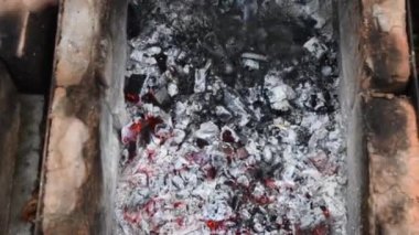 Ateş demiri kızgın kömürleri karıştırır ve barbekü ızgarasını Bratwurst sosisleriyle karıştırır.