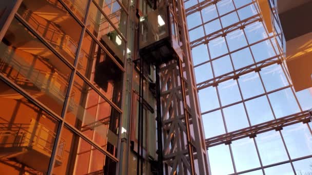 Elevador moderno movendo-se para baixo e para cima no edifício corporativo na luz solar da hora dourada do por do sol — Vídeo de Stock