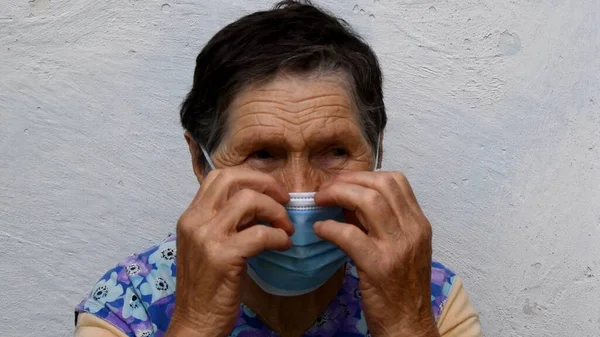 Yaşlı kadın yüzüne uygun bir tıbbi maske takıyor. — Stok fotoğraf
