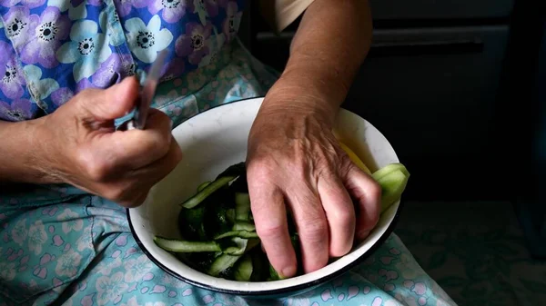 Aged hands take raw vegetables from old white bowl