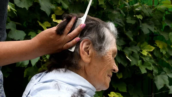 Резать волосы пожилой женщины дома во время карантина — стоковое фото