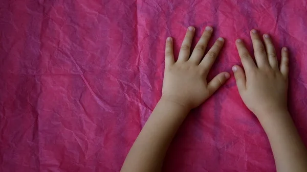 Вид зверху крупним планом дитячі руки на рожевому фоні з пробілом для копіювання — стокове фото