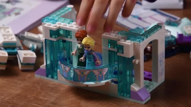 La mano del niño toma a la princesa Lego mientras juega bloques de Lego de dibujos animados Frozen Disney — Vídeo de stock