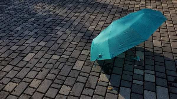 Paraguas azul turquesa después de la lluvia de pie en el camino pavimentado de piedra húmeda —  Fotos de Stock