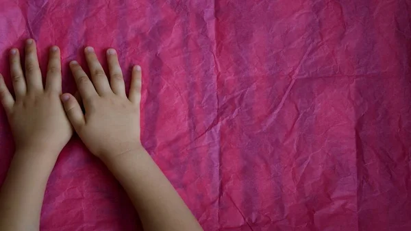 Вид зверху маленькі дитячі руки на рожевому фоні з пробілом для копіювання — стокове фото