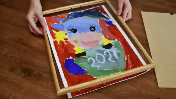 Time lapse female hands putting kid painting into wooden picture frame — Stock Video