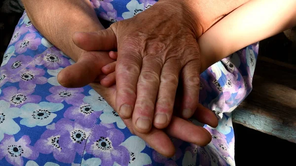 Mãos fechadas de bisavó segurando pequena mão de seu bisneto entre velhas palmas das mãos enrugadas — Fotografia de Stock
