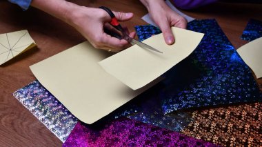 Kadın eli, sarı kâğıdı makasla kesiyor. Bulanık arkaplan üzerine simli kağıtlar hazırlama hobisi