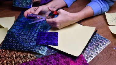 Kadın eli, sarı kâğıdı makasla kesiyor. Bulanık arkaplan üzerine simli kağıtlar hazırlama hobisi