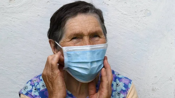 Senior mulher toque máscara descartável em seu rosto envelhecido — Fotografia de Stock