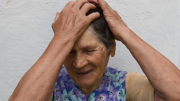 Портрет сміху старшої жінки, що піднімає обидві руки до голови — стокове фото