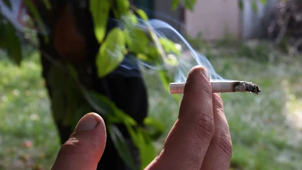Fumaça flutuante de cigarro ardente em dedos masculinos com unhas sujas — Fotografia de Stock