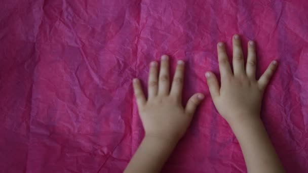 A gyermek kezek felső nézete érintse meg és simítsa ki a rózsaszín gyűrött papírt az asztalon másoló hellyel — Stock videók