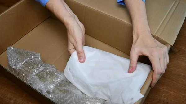 Kırılgan sofra takımlarını karton kutunun içine paketliyorum.