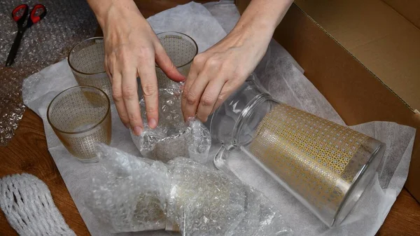 Женщины упаковывают стеклянную посуду в пластиковую упаковку. — стоковое фото