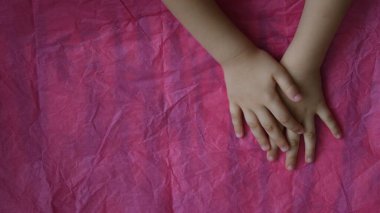 Çocuğun üst görünümü Pembe buruşuk kağıt zemin üzerinde fotokopi alanı ile çapraz eller